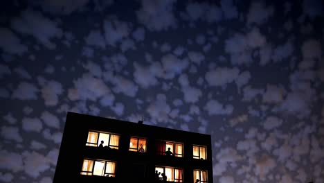 edificio de apartamentos por la noche con personas en las ventanas