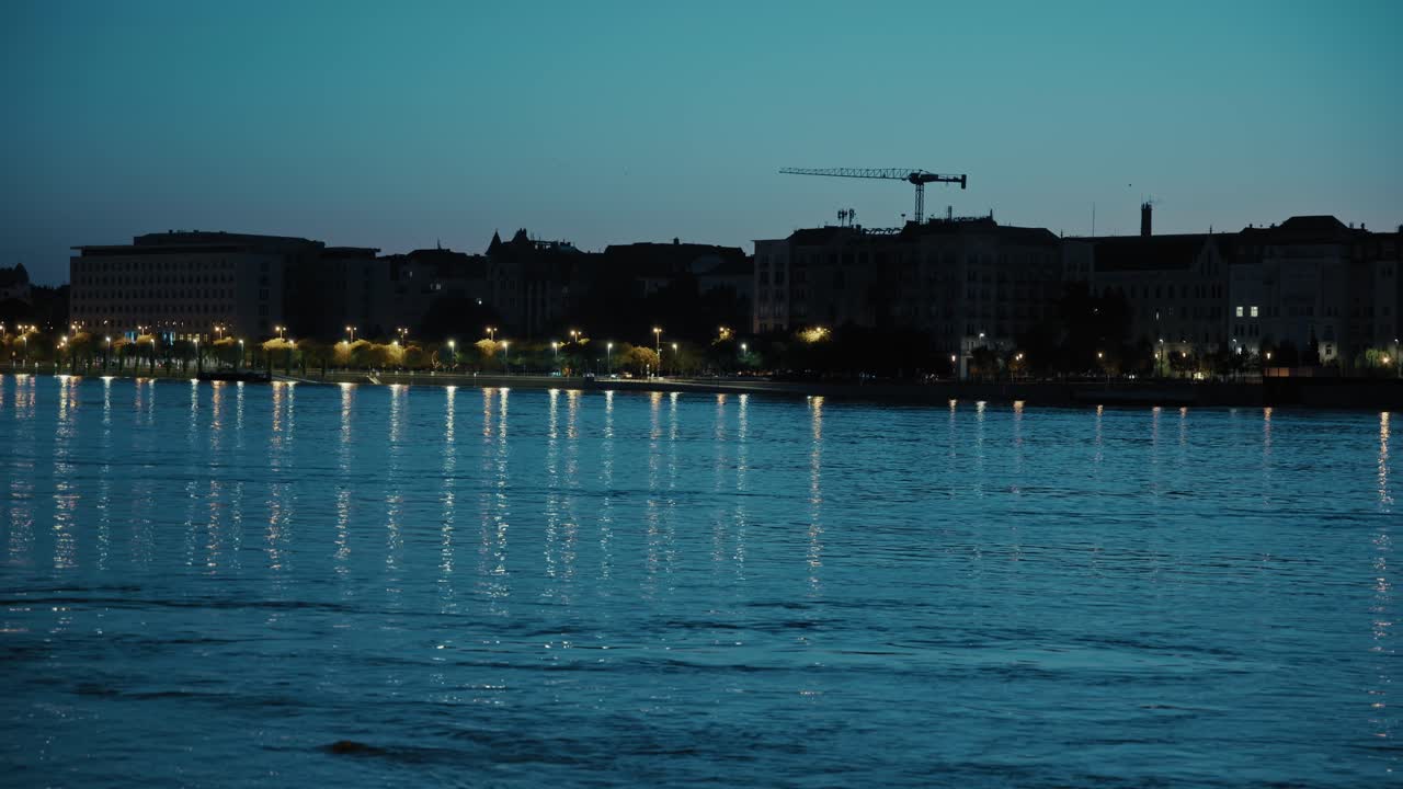 City skyline reflected in Danube River at dusk with streetlights illuminating scene