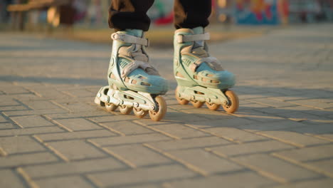 un primer plano que captura los pies de una persona con patines, deslizándose suavemente a lo largo de un camino pavimentado en un parque. con un enfoque suave en el fondo