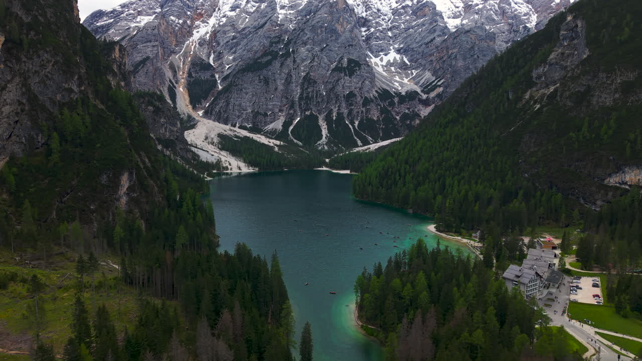 Aerial view of Lago di Braies with turquoise water, pine forest and dramatic mountains in the Dolomites, Italy