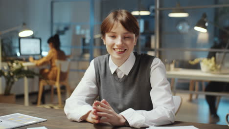 young cheerful businesswoman talking on camera in office