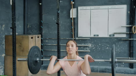 woman performing a barbell squat in a gym
