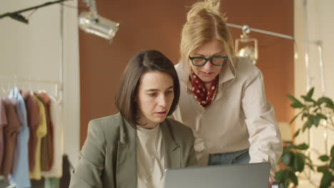 senior and young female colleagues working together on laptop