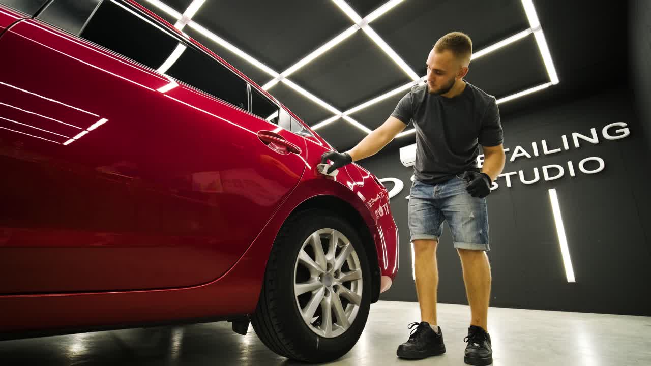Trabalhador de serviço automóvel aplicando nano revestimento em um detalhe do carro