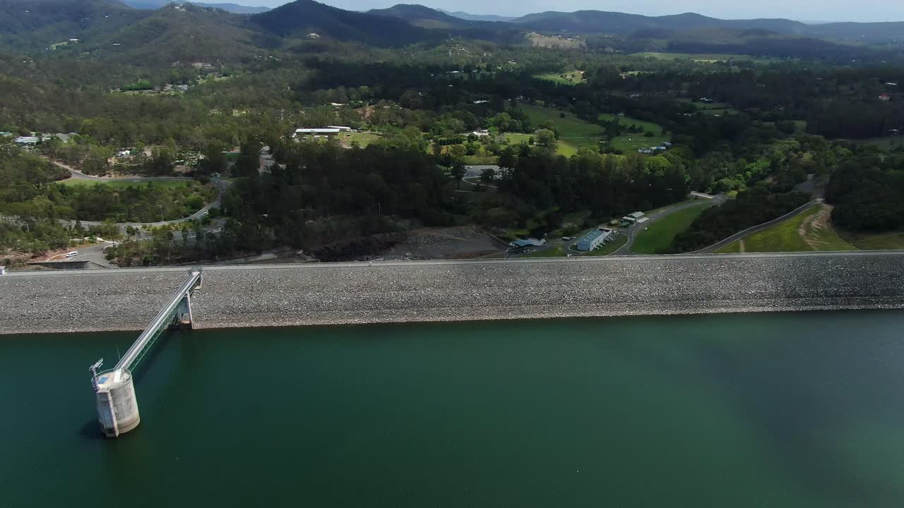 Fly over of Hinze dam wall ending looking vertically over edge of rock face