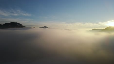 Toma-De-Drones-De-Un-Increíble-Paisaje-Cubierto-Bajo-La-Niebla-Con-Montañas-Circundantes-En-La-Mañana-En-Invierno-En-Eslovenia-Capturado-En-4k,-Drones-Subiendo-Sobre-La-Niebla