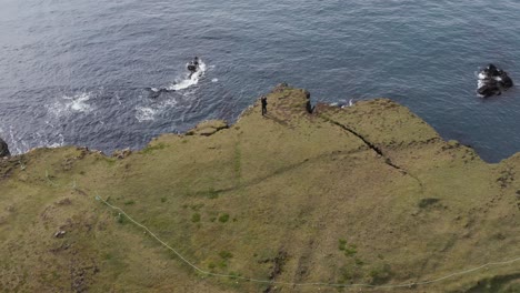 Photographer-stands-on-moss-cliff-in-Iceland-taking-photos-of-sea-birds