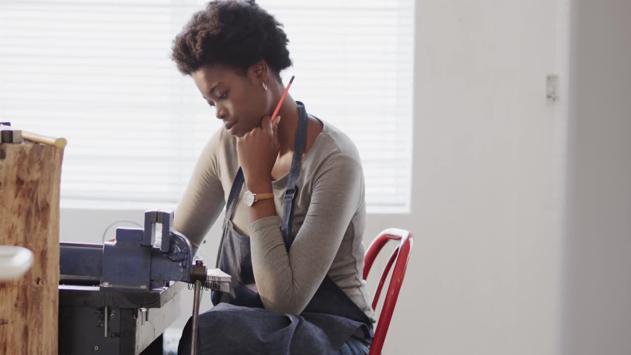 Busy african american female worker doing design of jewellery in studio in slow motion