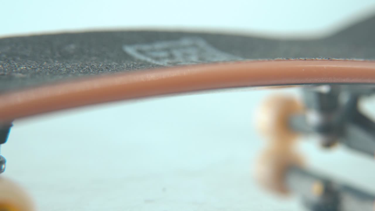 макро-детальный снимок мини-скейтборда, крошечные белые колеса, пальчиковая доска на 360 крутящейся стойке, блестящее зеркальное отражение, профессиональное освещение, кинематографическое 4k видео.