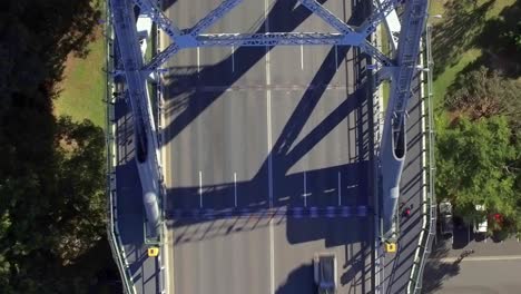 ángulo descendente en el puente story: toma aérea que cruza el puente y revela el tráfico, con el parque debajo del puente