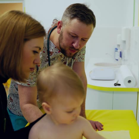 baby doctor doing check-up. male pediatrician examining spine of a little boy in modern medical center. parents listen to the doctor's opinion of their child.