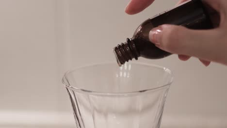 pouring serum or essential oil into a glass