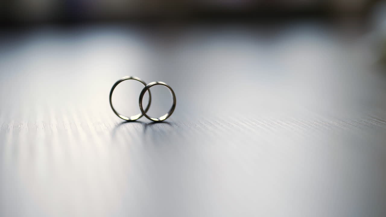 Two Interlocked Wedding Rings Standing on a Reflective Surface