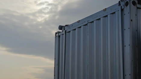 side of a metallic container against a cloudy sky