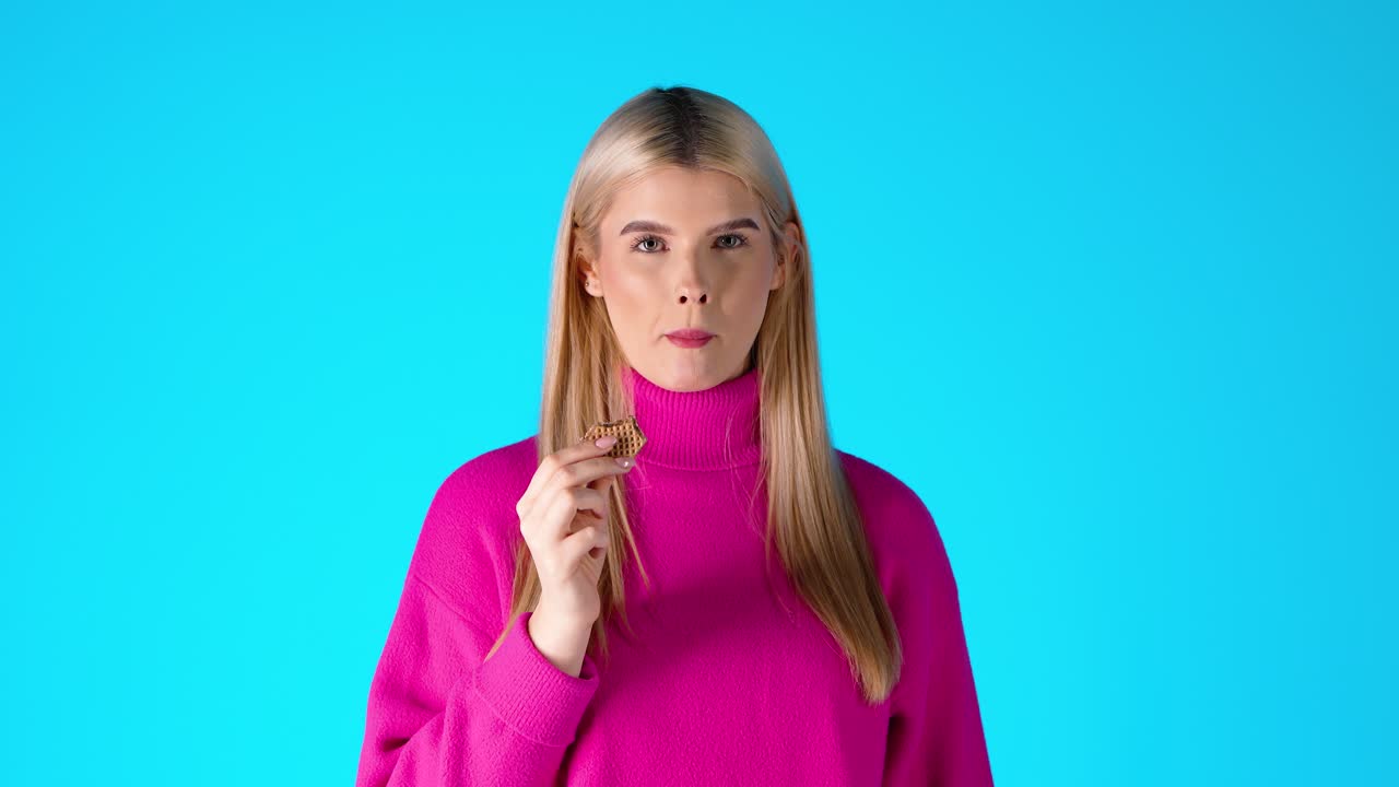 Attractive Blonde Woman Eating Wafer, Colorful Studio Portrait