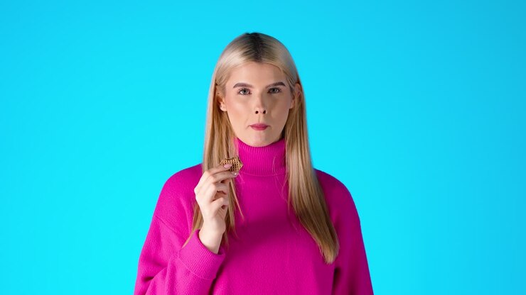 Attractive Blonde Woman Eating Wafer, Colorful Studio Portrait