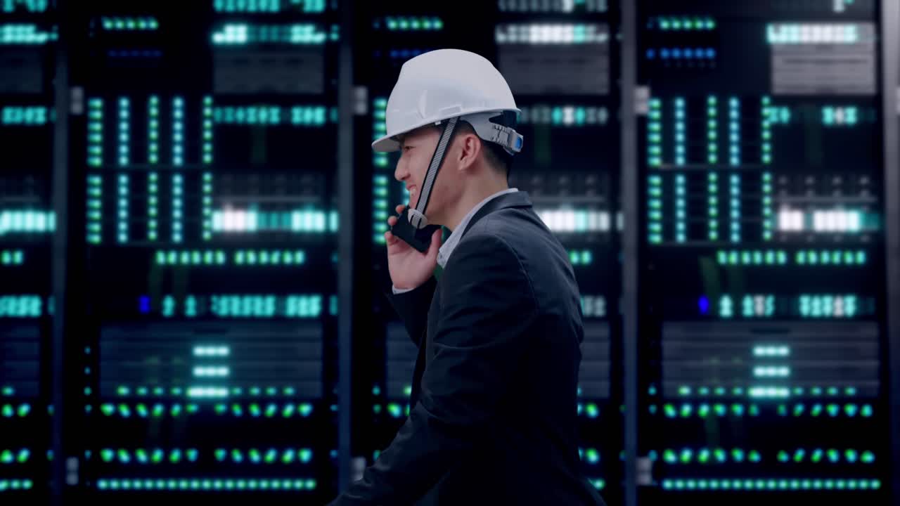 Side View of Asian Businessman Talking On Smartphone While Walking in Server Room Data Center