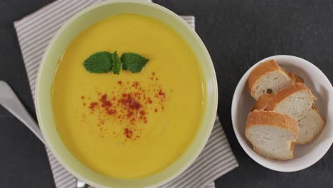 video of cream vegetable soup in bowl on grey table with bread