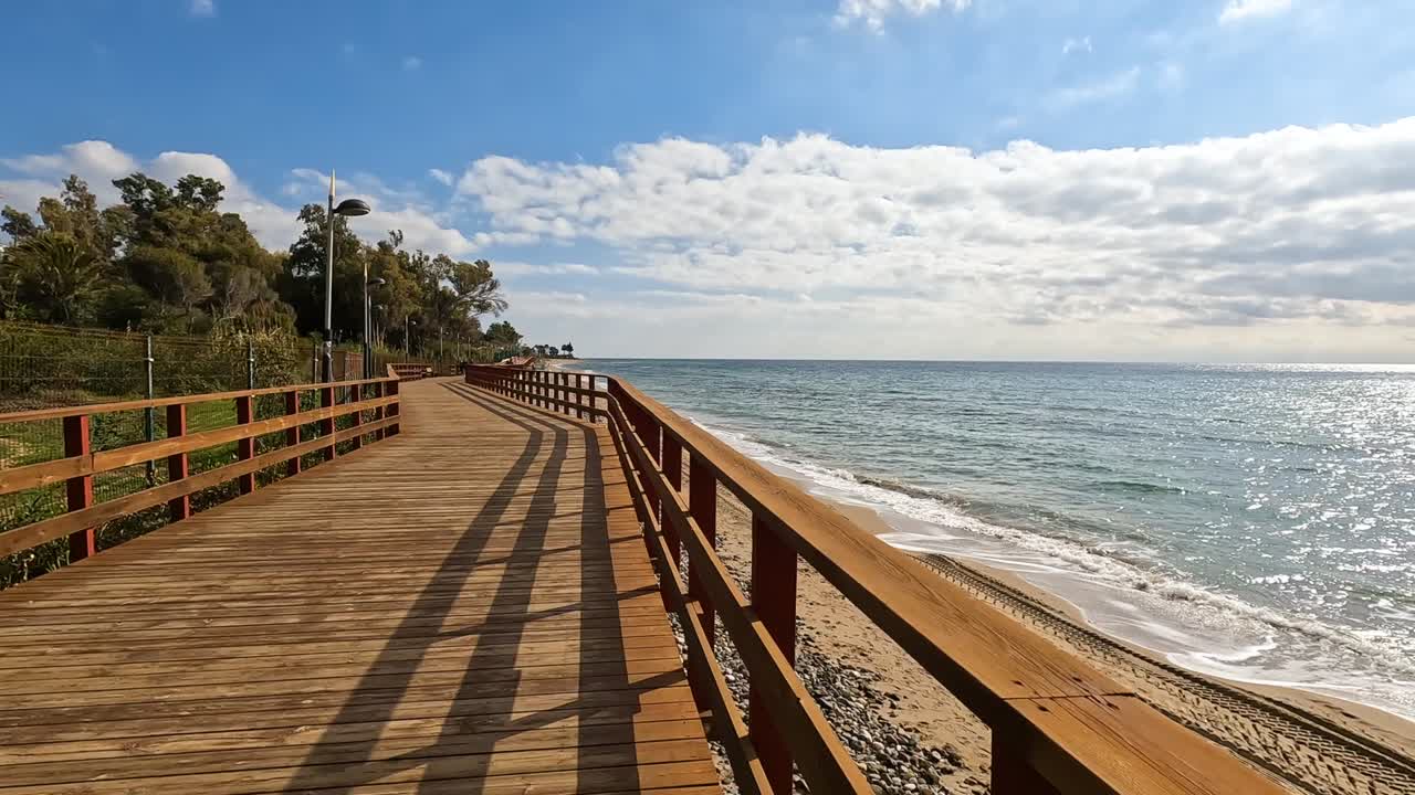 Ujęcie 4K pustej drewnianej kładki na brzegu plaży w Marbelli, Hiszpania.