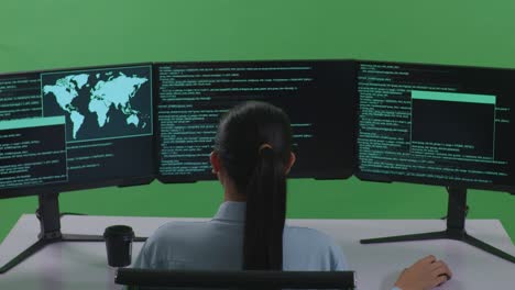 Back View Of Tired Asian Woman Developer Stretching While Write Code With Multiple Computer Screens In Green Screen Studio