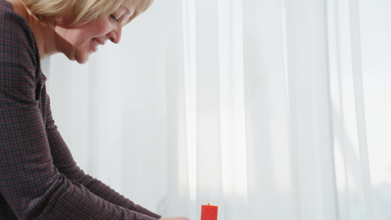 젊은 여자가 부드럽게 부 테이블에 은 불을 놓고 따뜻하게 미소 짓고, 색 캐비과 아한 가정 분위기를 가진 밝은 현대 부