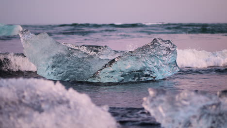 Small-piece-of-glacier-ice-rests-on-Diamond-Beach-as-wave-breaks-around-it