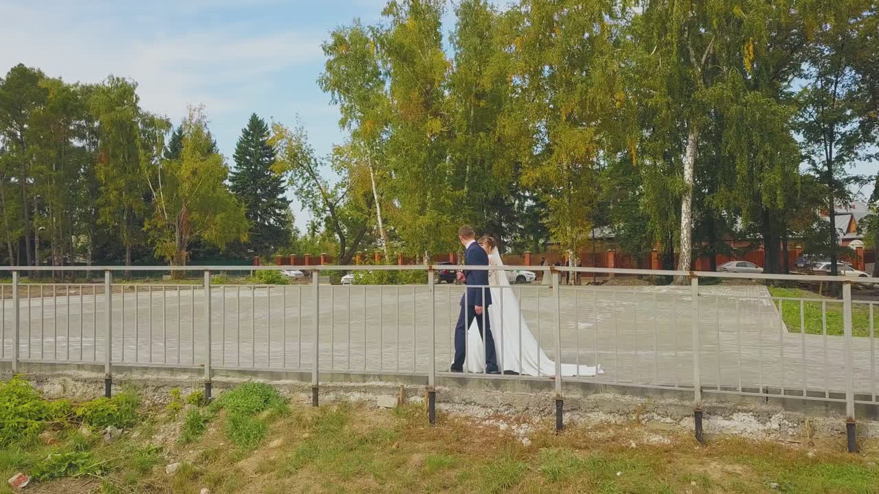 신랑 과 함께  ⁇  드레스 를 입은 여자 가 공원 공중 전망 을 따라  ⁇ 고 있다