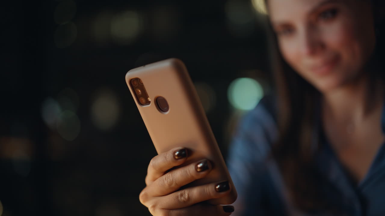 Woman freelancer reading sms on cellphone at dark apartment workplace closeup