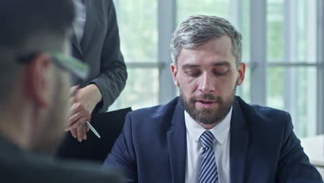 close up view of a businessman with gray hair sitting at a table in a business meeting