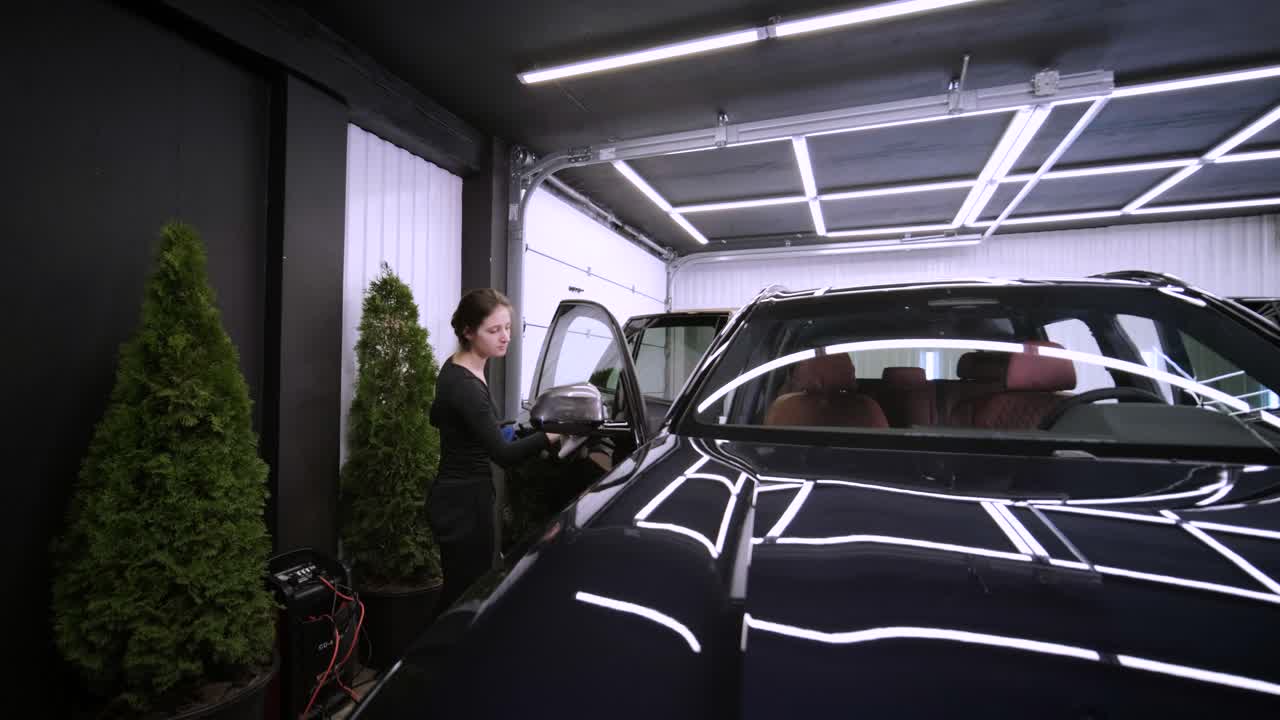 el lavador de coches profesional con guantes negros limpia el coche después de lavar y forrar la cerámica. conceptos de: trabajo profesional, varias herramientas de lavado, limpieza para brillar.