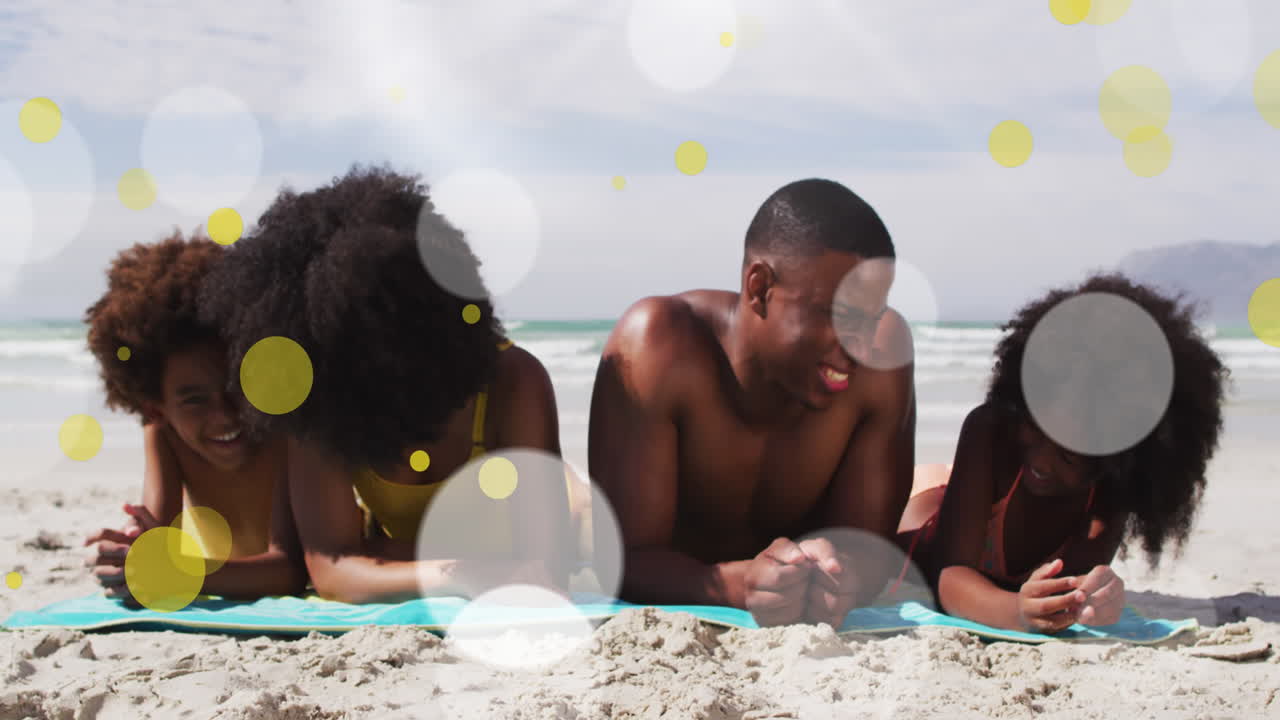 Animation of happy african american family lying at beach over light spots