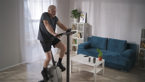 Training-Mit-Stationärem-Fahrrad-Zu-Hause.-Ein-Mann-Mittleren-Alters-Trainiert-Und-Dreht-Die-Pedale,-Um-Sich-Fit-Und-Gesund-Zu-Halten,-Cardio-Training