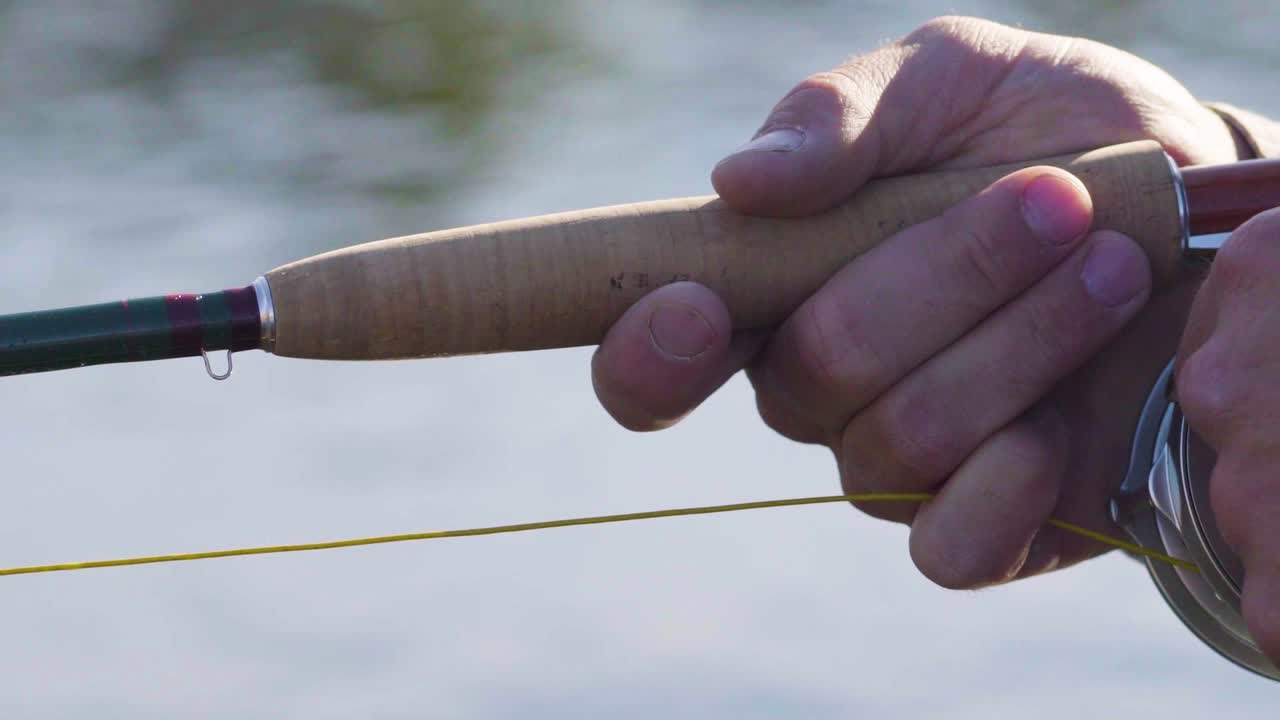 Primo piano di un pescatore a mosca con ottima tecnica che manovra la sua canna e il suo mulinello