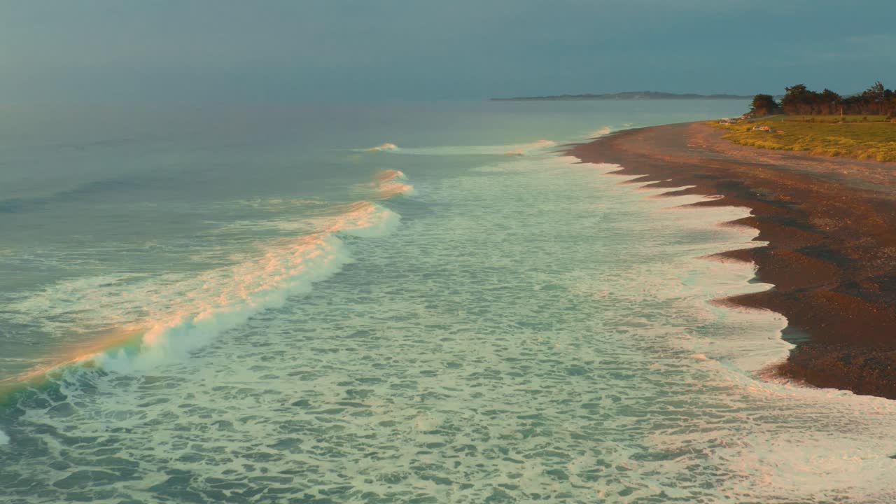 Aerial View of Waves Crashing on a Dark Sand Beach at Sunrise