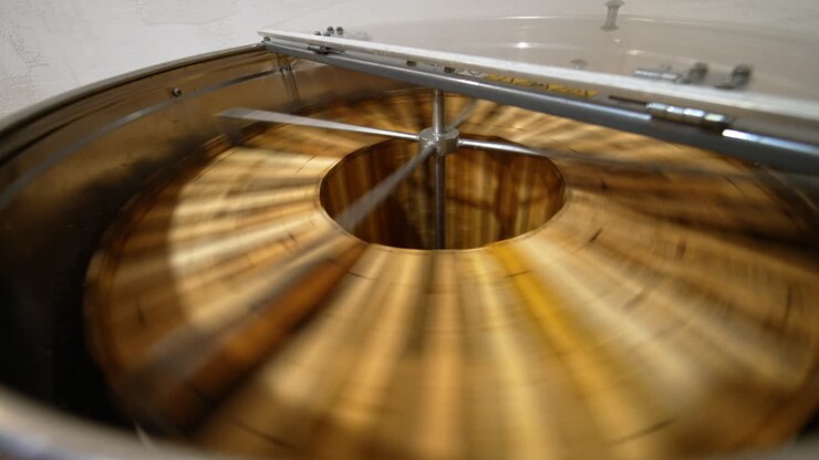 Honey removal machine rotating the frames with organic honey. Harvesting healthy product on the rural bee farm. Close up.