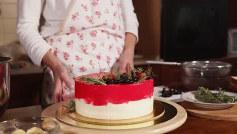 woman decorating a beautiful multi-layered cake with berries