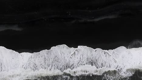 aerial view of black sand beach with crashing waves