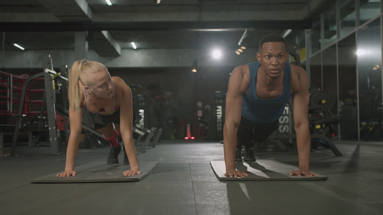 Front view of caucasian female monitor and an athletic african american man in the gym.