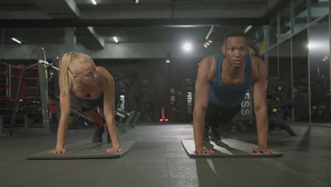 Front-view-of-caucasian-female-monitor-and-an-athletic-african-american-man-in-the-gym.