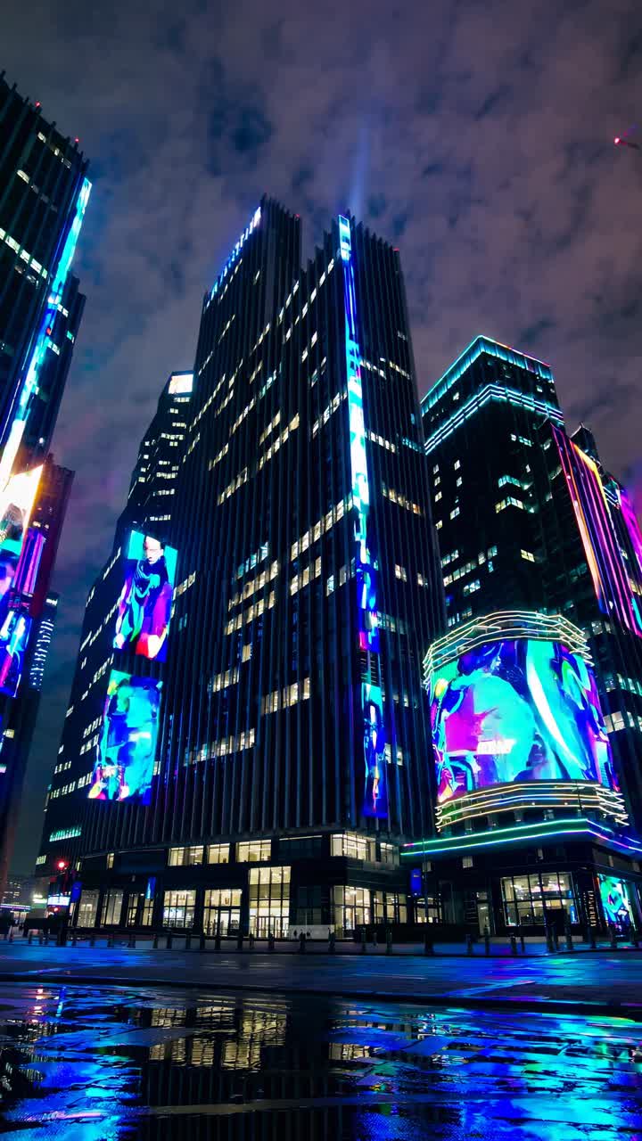 Night cityscape with skyscrapers lit by neon lights, captured from a low-angle