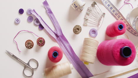 video of tape measure, scissors, safety pins, reels of thread and zips on white background