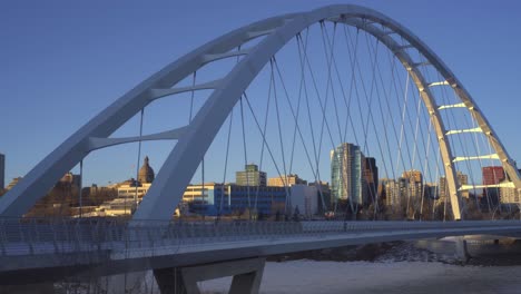 Twilight-Post-Modern-Futuristic-Walter-Dale-bridge-sunset-winter-afternoon-over-North-Saskatchewan-River-frozen-over-reflecting-light-on-metal-straps-with-the-background-skyline-of-downtown-Edmonton