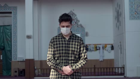 a young man praying in the mosque during a pandemic