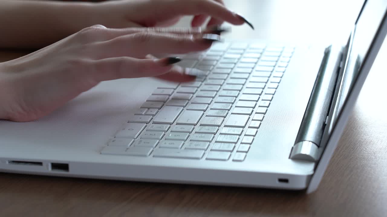 Female hands of a woman typing on a laptop keyboard while sitting at her desk