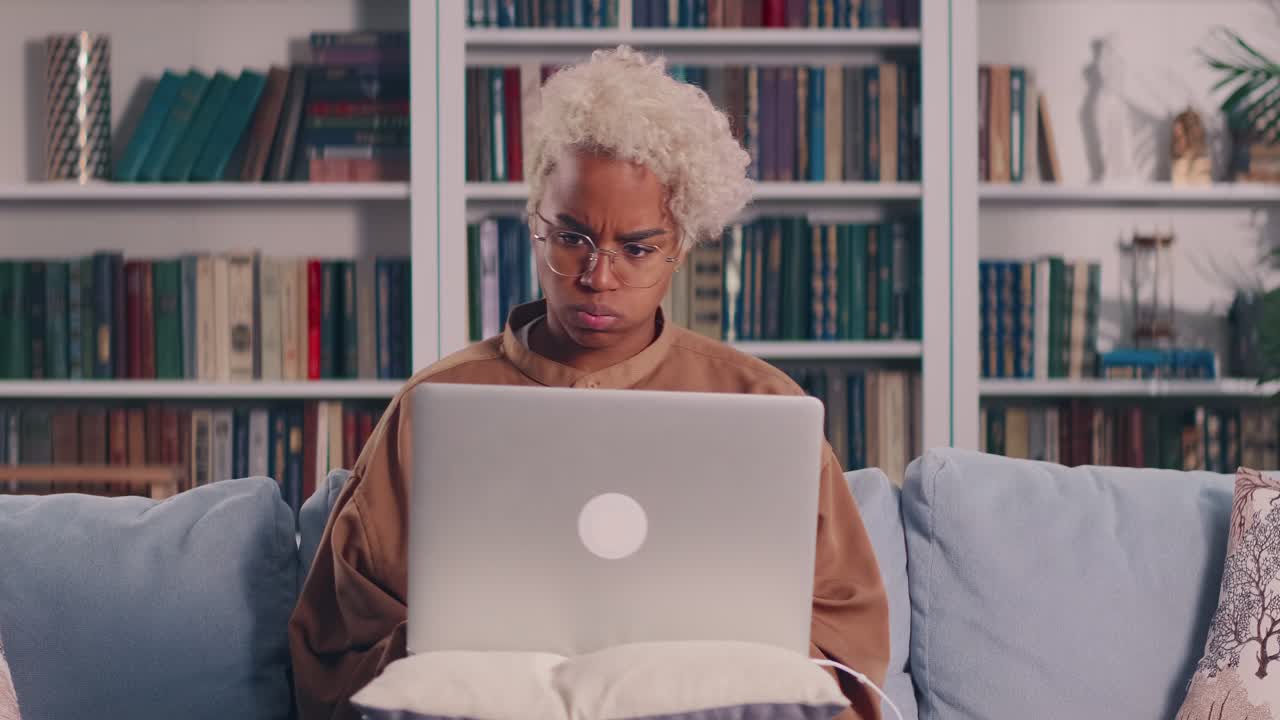 Donna africana che usa il laptop a casa, ansiosa per il malfunzionamento del dispositivo elettronico.