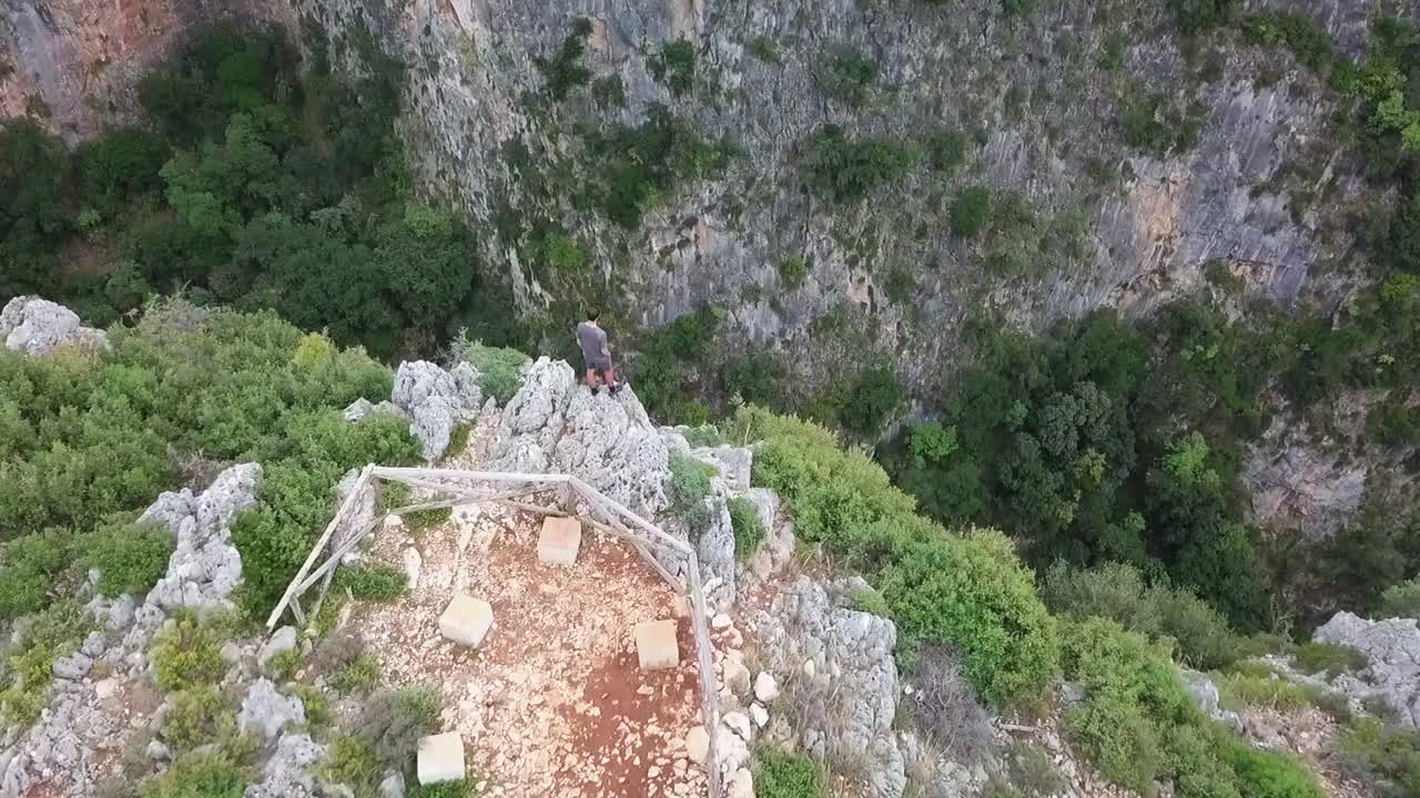 Person steht auf einer riesigen Klippe und blickt in den Gjipe-Canyon