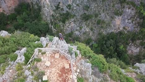 humano de pie sobre un enorme acantilado mirando hacia el cañón gjipe