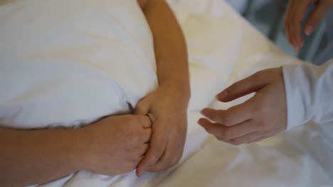 Hände-Einer-Asiatischen-Ärztin,-Die-Händchen-Hält.-Patientin,-Die-Im-Bett-Im-Krankenhaus-Liegt