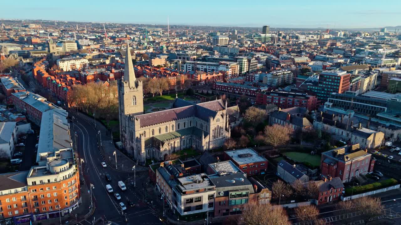 Luftdronebilde av St. Patrick's Cathedral i Irlands hovedstad, Dublin. Filmet ved en gyllen vintersolopgang med parken i sikte med gress og trær. Glødende irsk arkitektur og by