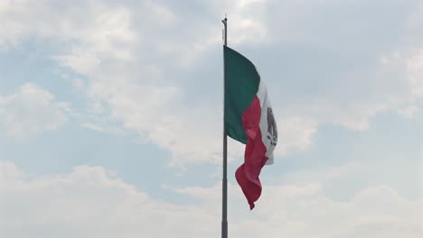 flag of mexico flying on flagpole against the bright sky. - static shot
